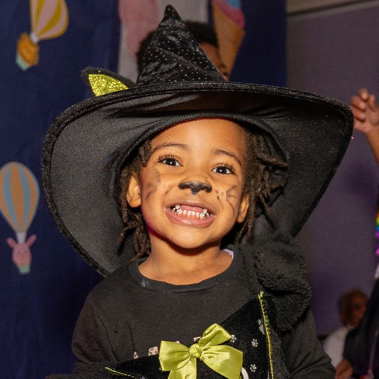 Child in witch costume with green bow