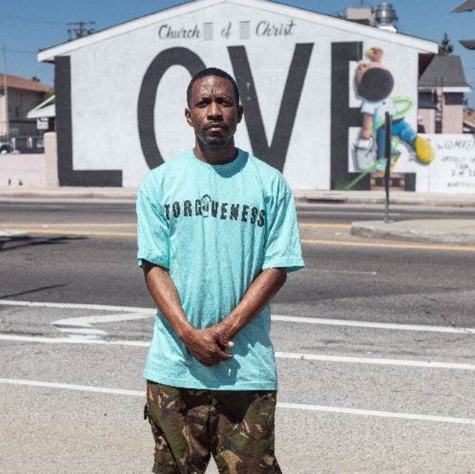 Man in turquoise shirt near LOVE mural